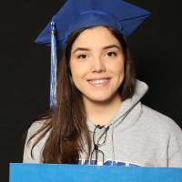 student in grey sweatshirt and blue graduation cap